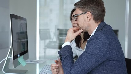 Business colleagues collaborating on data analysis, watching financial graphs and charts on computer monitor. Businesspeople concept - Powered by Adobe