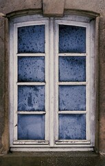 Frosted vintage window with weathered wooden frame and icy glass panes in winter