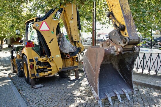CAT backhoe loader parked on cobblestone street