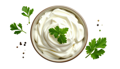 Creamy white sauce in a bowl, garnished with parsley, surrounded by peppercorns, overhead view, isolated on black