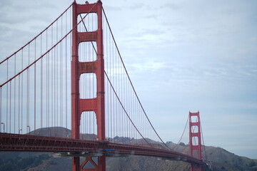 This classic view captures the unmistakable grandeur of the Golden Gate Bridge, framed against a soft, subtly textured sky. The composition emphasizes the colossal scale of the southern tower.