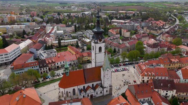 Cinematic aerial drone orbit around the towering spire of the Church of the Nativity of the Blessed Virgin Mary in historic Pisek, Czech Republic.