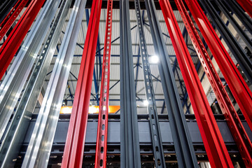 Modern industrial shelving components in vibrant red, sleek silver, and dark gray, forming a striking abstract pattern. Highlights warehouse infrastructure, logistics, and robust metal construction.