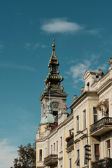Fototapeta premium Golden church tower and ornate building facade under blue sky in old Belgrade, Serbia