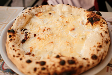 Appetizing pizza with melted cheese and crispy crust, perfect comfort food moment on a cozy outdoor cafe table.