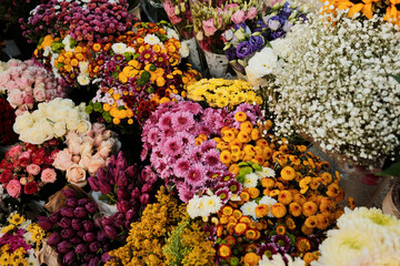 Rich composition of colorful flowers and bouquets with roses, daisies, and chrysanthemums on street market