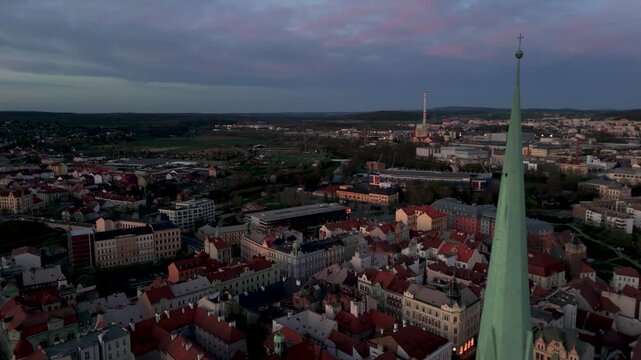 High Altitude Aerial Drone Pass Shot of the Gothic Cathedral of St. Bartholomew Spire in Pilsen, Czechia, Illuminated at Dusk.