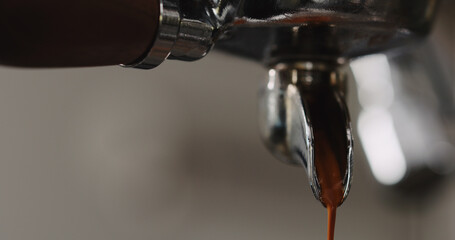 pulling espresso shot with single spout portafilter from coffee machine closeup
