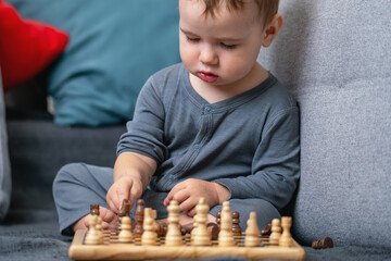 Toddler sitting cross-legged and playing chess.