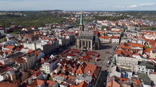 Aerial Drone Approach Shot Flying Over Colorful Rooftops Towards the Gothic Cathedral of St. Bartholomew Spire and Republic Square in Pilsen, Czechia.