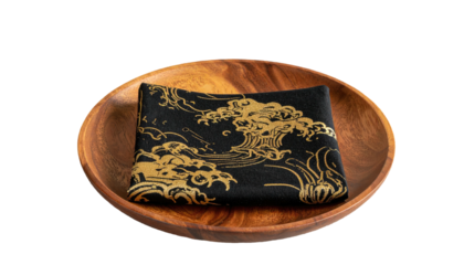Black cloth w/ gold waves pattern, neatly folded in a wooden dish. Dark background