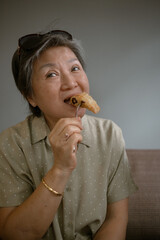 An elderly woman smiling happily while enjoying a delicious snack in a modern cafe