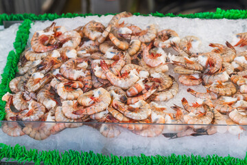 Fresh raw shrimp displayed on ice in a seafood market stall.