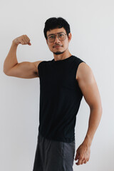 A fit and confident Asian man flexes his strong arm muscles, showcasing impressive physical strength and self assurance.