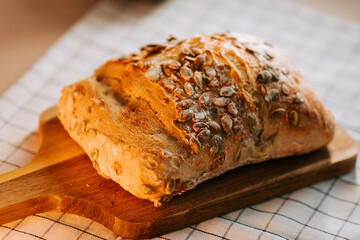Fresh bread topped with watermelon seeds on a wooden board in a cozy kitchen setting