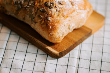 Freshly baked bread with watermelon seeds on wooden board in cozy kitchen setting