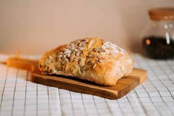 Freshly baked bread with watermelon seeds rests on a wooden cutting board