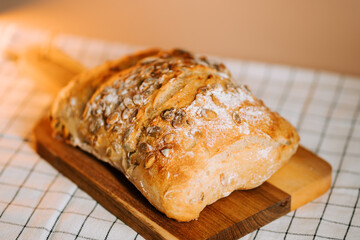 Freshly baked bread with watermelon seeds on a wooden board in a cozy kitchen setting