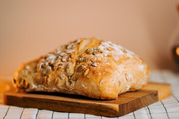 Fresh bread topped with watermelon seeds resting on a wooden board in a cozy kitchen