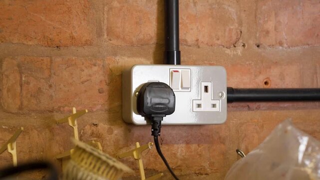 Hand switch off and unplugging a plug from the socket outlet in a garage, conserving power usage and electricity