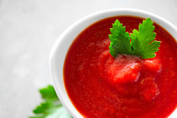 Tomato paste, sauce, Homemade tomato paste in a white bowl and fresh ingredients on a grey table. Ketchup, Red sauce for pizza or pasta made from fresh bio tomatoes. Border design. Top view 