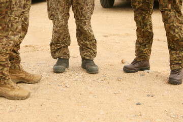 Soldiers standing, wearing camouflage pants and boots, close-up of legs up to the knee