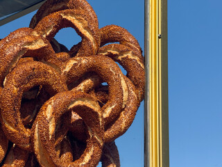 Fresh simit bagels stacked on a street stand under blue sky