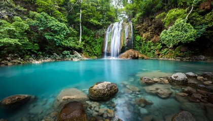 Fototapeta premium tropical waterfall clear turquoise pool smooth pebble shore lush green foliage tranquil natural paradise peaceful atmosphere