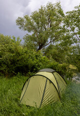 A green summer tent in the forest on green grass
