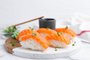 Delicious nigiri sushi with salmon, microgreens and soy sauce on white marble table, closeup