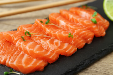 Fresh salmon sashimi with microgreens on wooden table, closeup