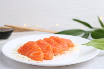 Fresh salmon sashimi with sliced radish on light grey table, closeup