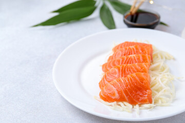Fresh salmon sashimi with sliced radish on light grey table, closeup. Space for text