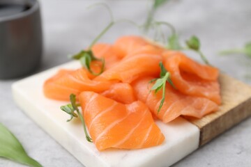 Fresh salmon sashimi with microgreens on grey table, closeup