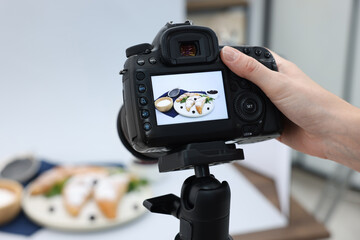 Woman shooting tasty croissants and ingredients with camera in studio, selective focus. Professional food photography