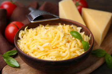 Grater, grated and pieces of cheese on wooden table, closeup