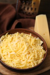 Grated and piece of cheese on wooden table, closeup