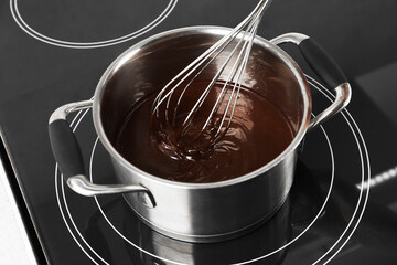 Mixing melted chocolate with whisk in pot, closeup