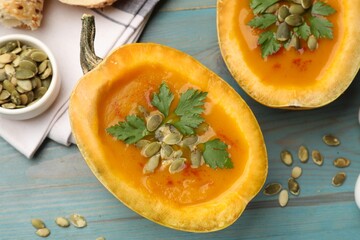 Tasty pumpkin cream soup with seeds and parsley on light blue wooden table, flat lay