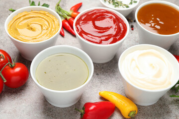 Different sauces, spices and herbs on light table, closeup