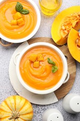 Delicious pumpkin cream soup with basil served on grey table, flat lay
