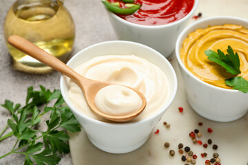Different sauces, spices and herbs on light table, closeup