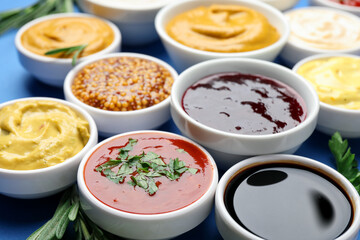 Different sauces and herbs on blue background, closeup