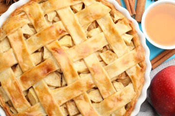Tasty homemade apple pie and ingredients on light blue background, flat lay