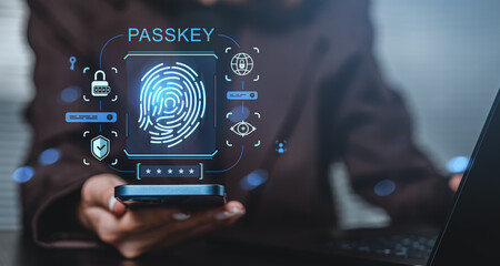 Fingerprint passkey authentication technology concept with biometric security icons on transparent interface over smartphone and laptop in office setting.