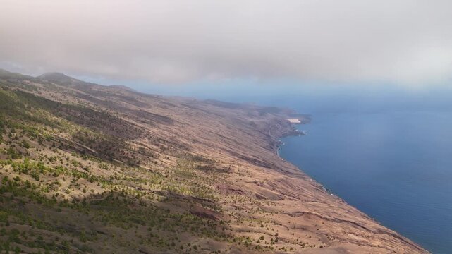 Aerial drone pan over the volcanic slopes and ravines of La Restinga looking out over the clear Atlantic Ocean, El Hierro, Canary Islands, Spain.
