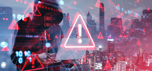 Hacker in hoodie using laptop with digital warning symbols and b