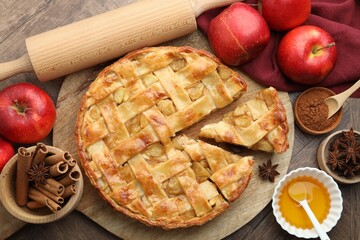 Delicious homemade apple pie and ingredients on wooden table, flat lay