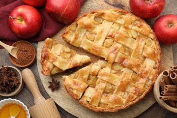 Delicious homemade apple pie and ingredients on wooden table, flat lay