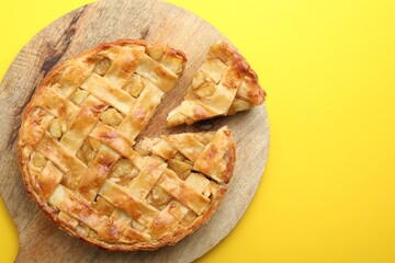 Delicious homemade apple pie on yellow background, top view. Space for text